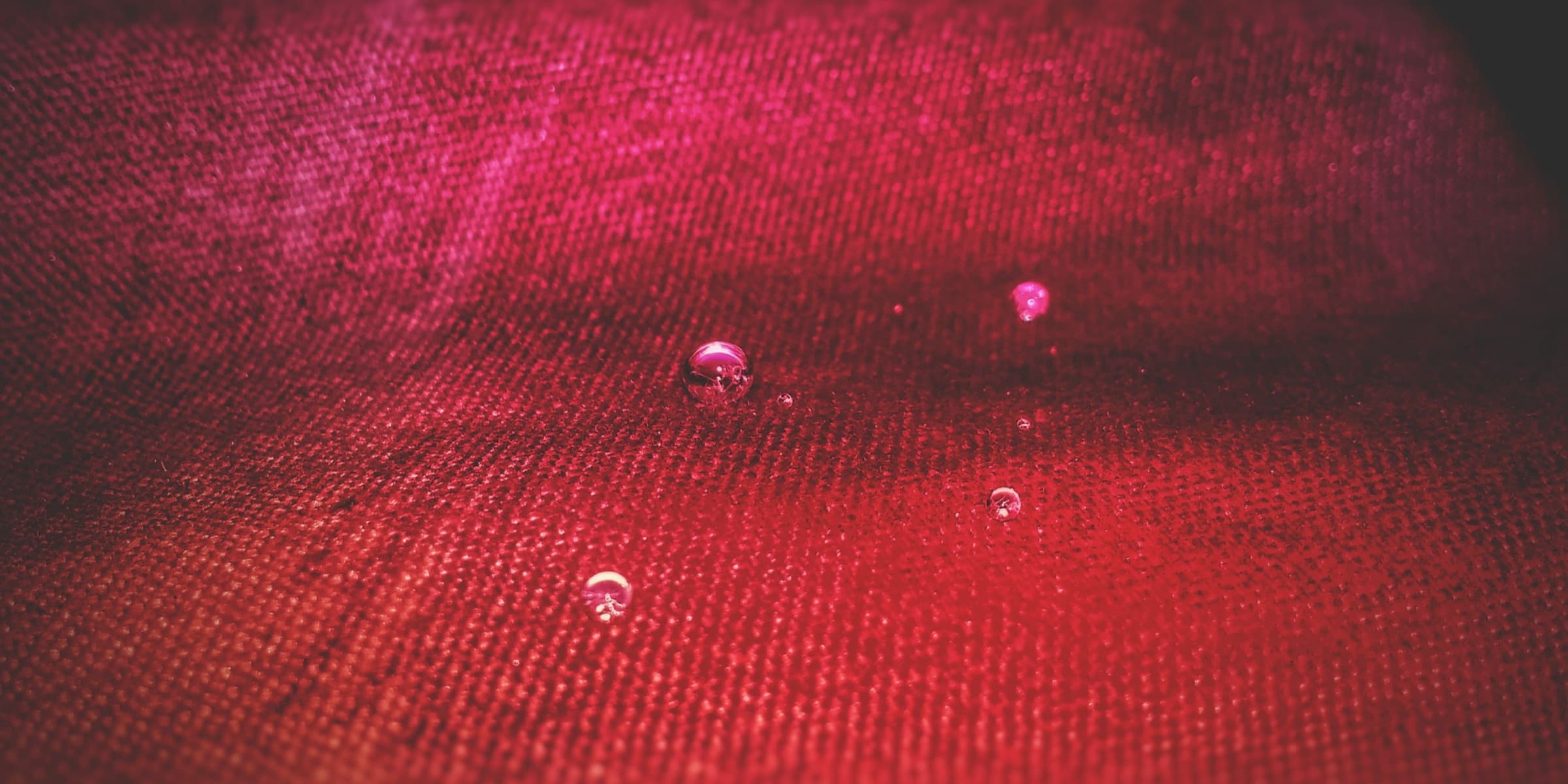 Water droplets resting on red fabric